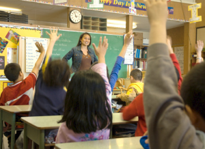 Teacher standing in front of class teaching finding factors.